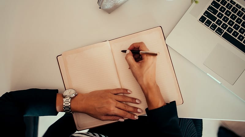 A printed contract page held open with a paperweight, a signature line at the bottom and a pen lying across the margin.
