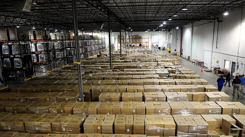 A parcel sorting belt with boxes moving past a scanner in a warehouse, a handheld device on a rail.