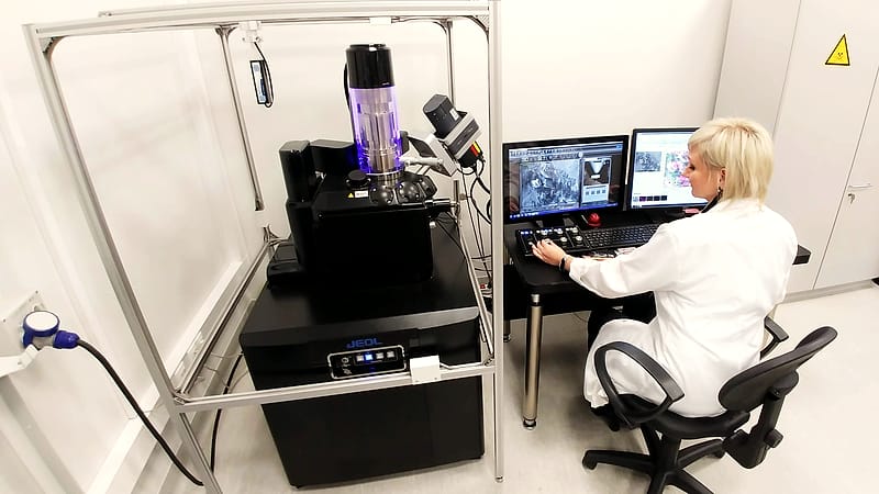 A laboratory bench with a calibrated instrument, a notebook of handwritten figures and a pair of safety glasses.
