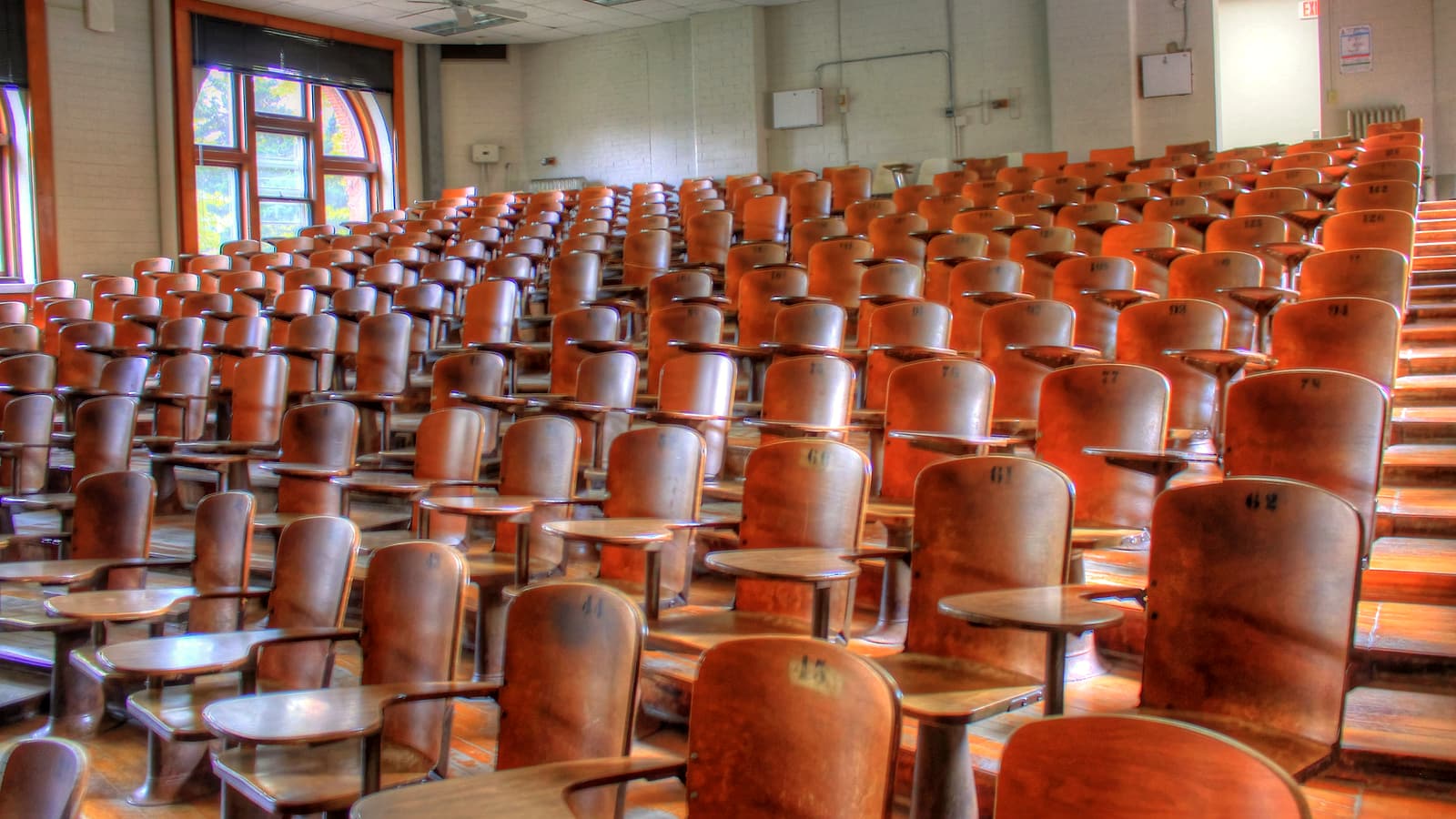 A wooden lectern with a small reading light facing a curved bench of empty high-backed chairs.