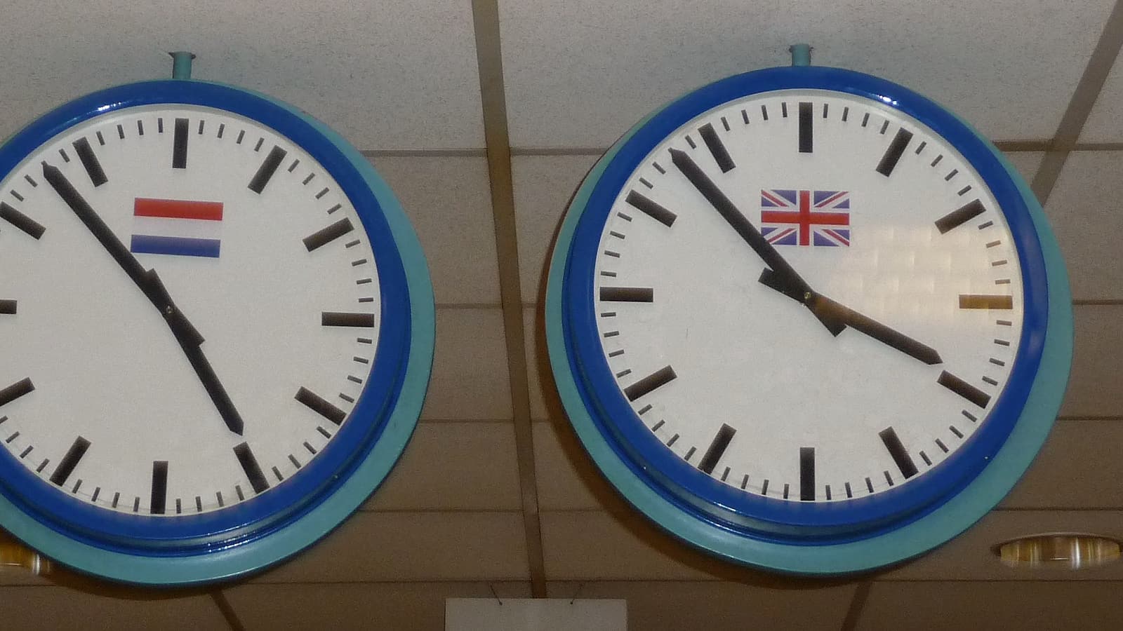 Two office telephones on a desk beside a stack of paper files and a wall clock showing a late hour.